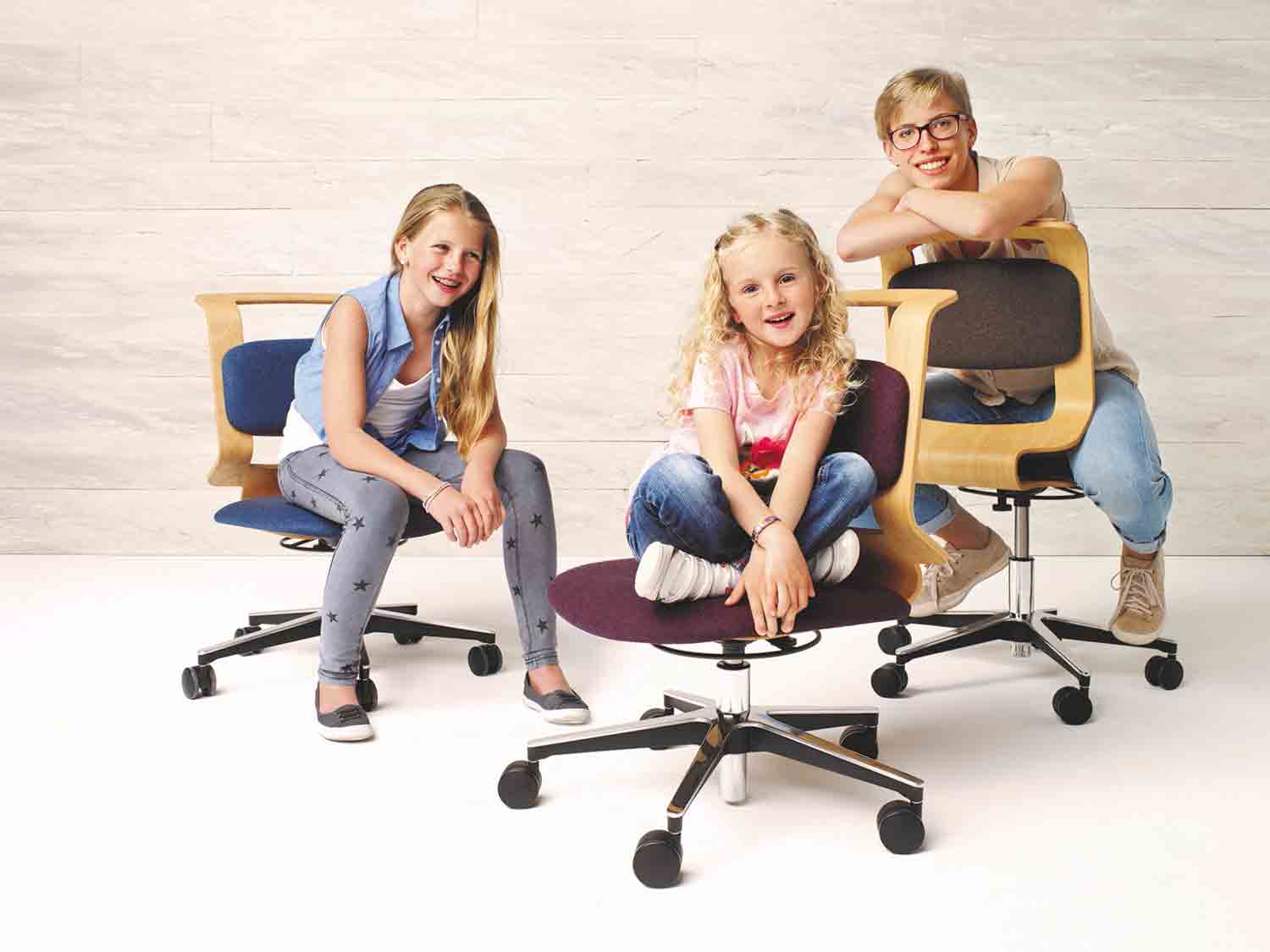 Drei Kinder auf einem mitwachsendem Stuhl für das Kinderzimmer.