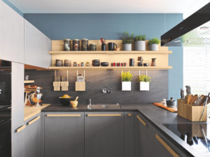 Moderne Küche in U-Form mit Küchenzeile und Kochfeld in grauer Optik. Griffe aus Naturholz und Keramikarbeitsplatte in schwarz. 